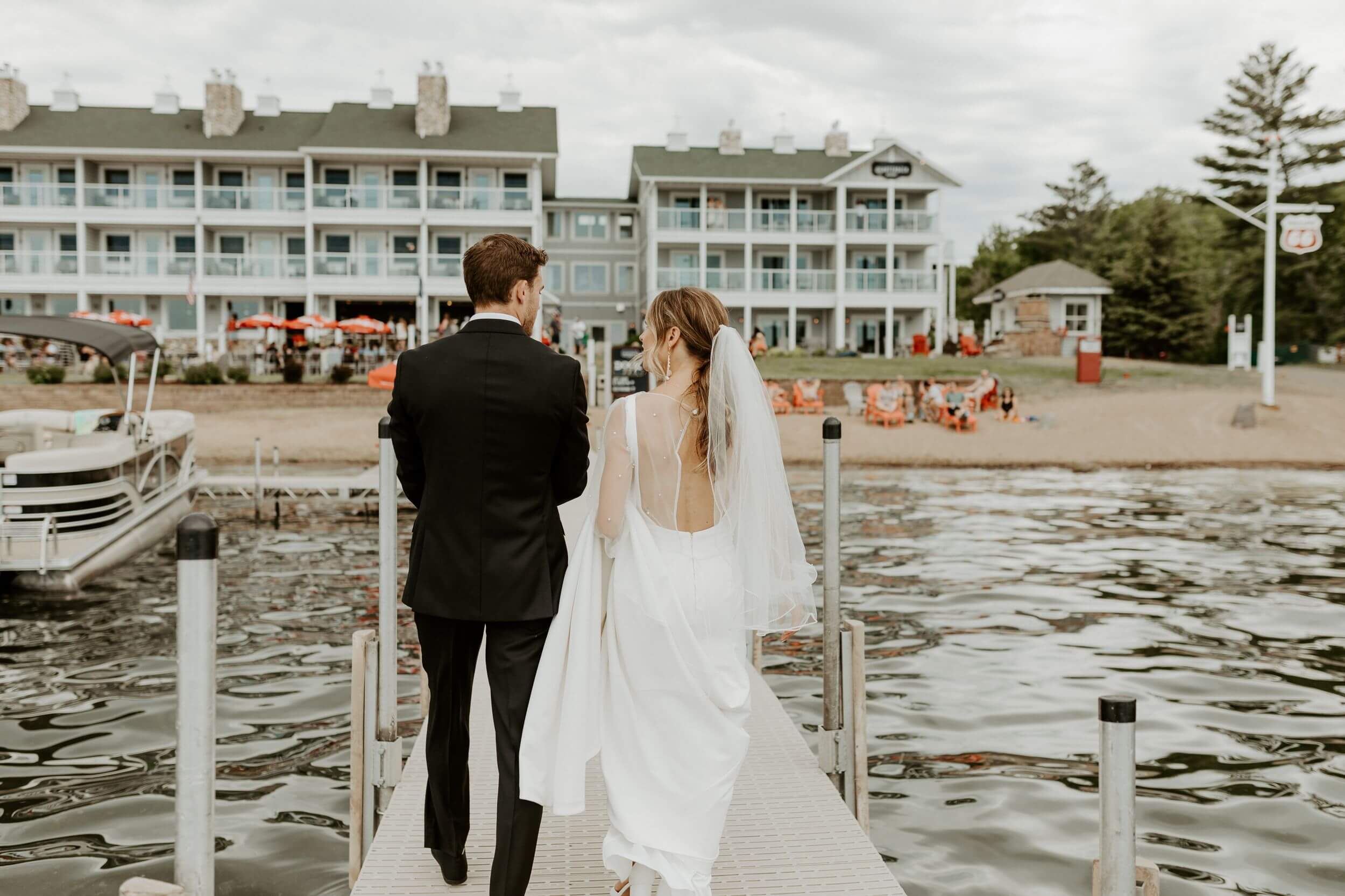 Bride and groom walk on dock towards their wedding venue in Brainerd, Minnesota