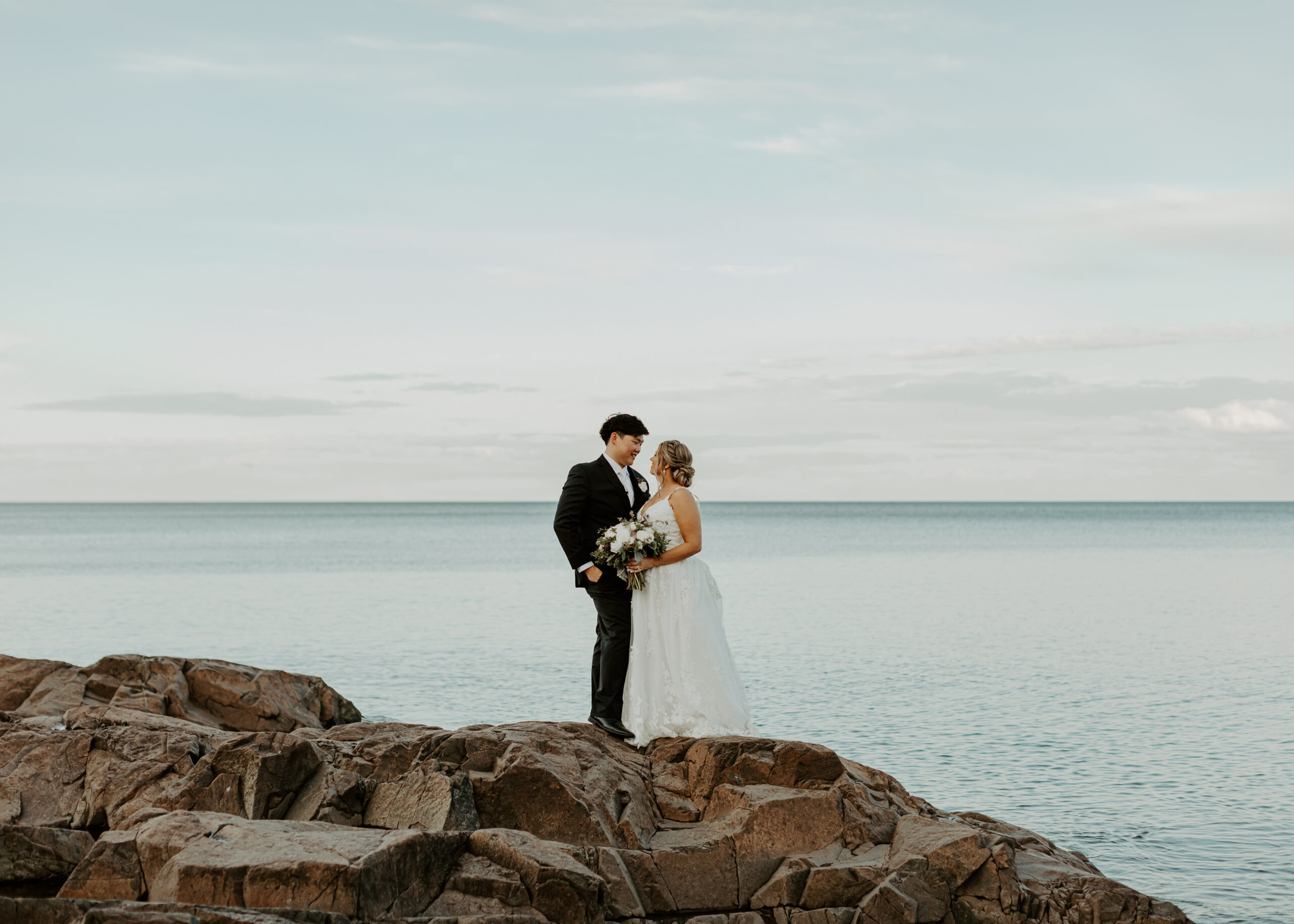 Bride and Groom pose on the shore of Lake Superior during sunset in Duluth, Minnesota