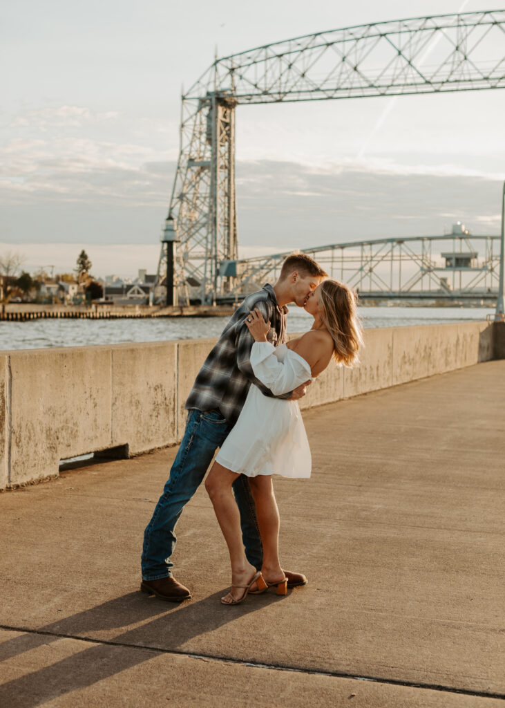 Couple kisses in front of Aerial Lift Bridge in Duluth Minnesota during engagement photo session
