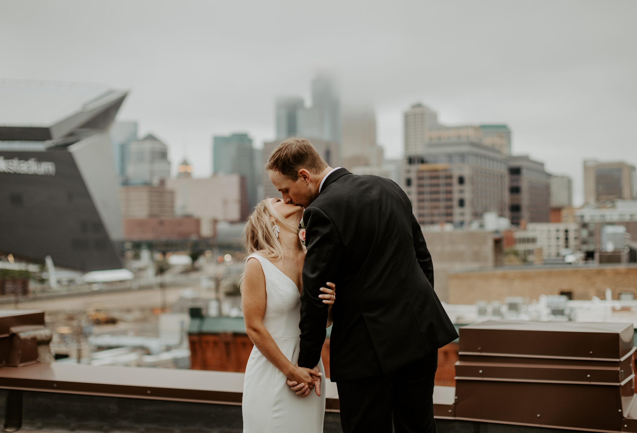 Bride and Groom kiss on the rooftop of Dayblock Event Center in Downtown Minneapolis, Minnesota overlooking US Bank Stadium