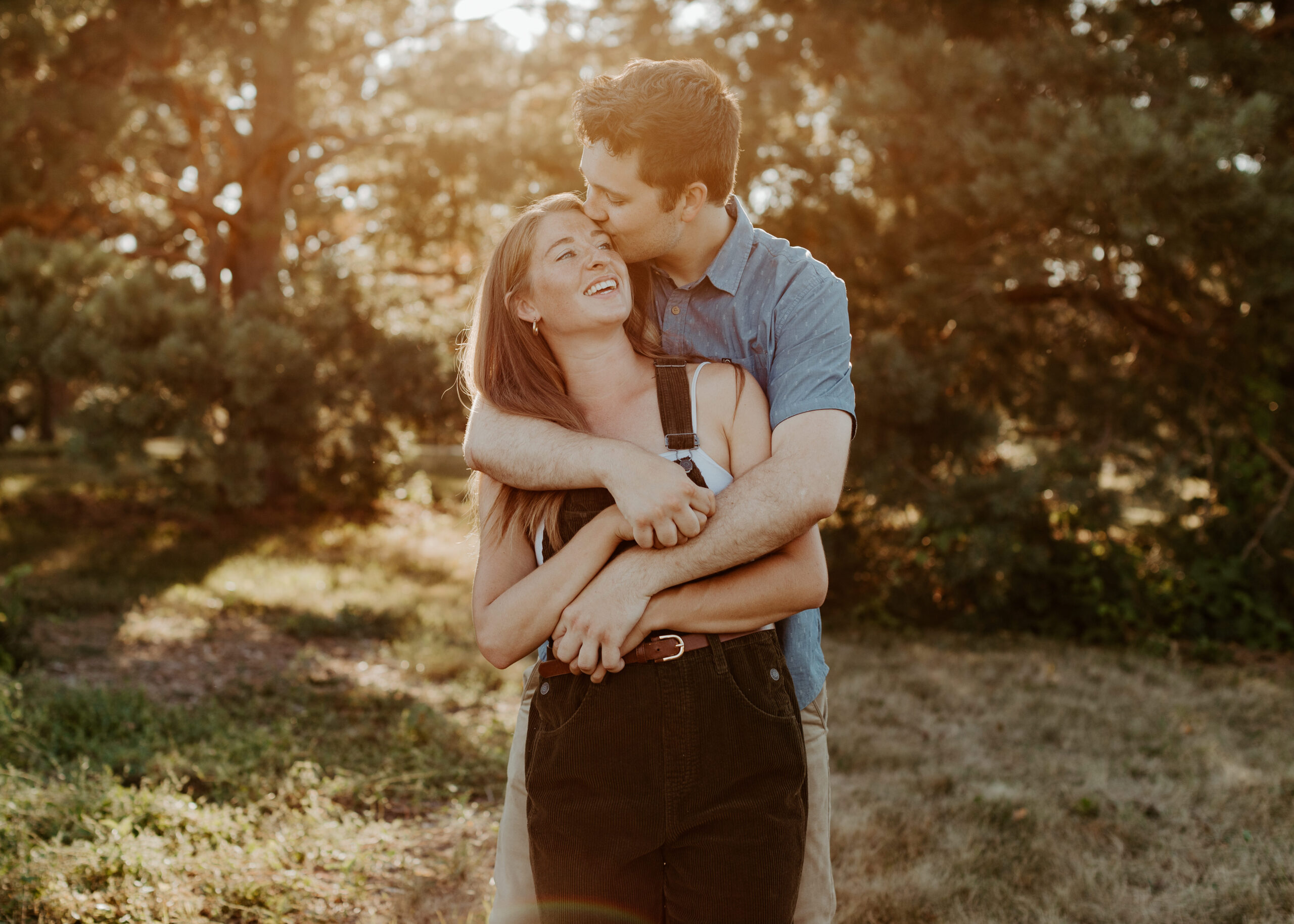 Couple embraces in a field at sunset at the Minnesota Landscape Arboretum in Chaska, Minnesota during engagement photos