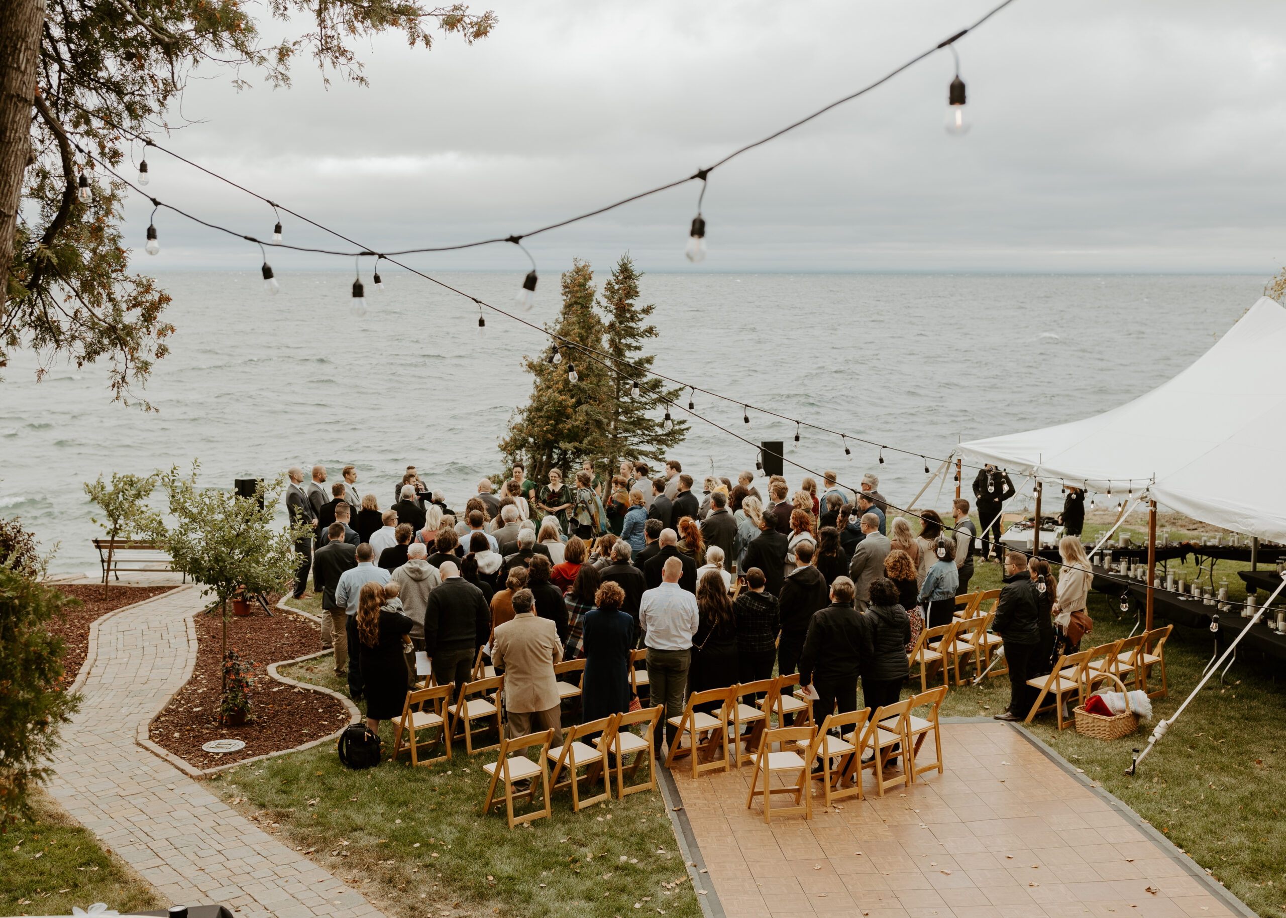 Aerial view of guests standing for the beginning of a wedding ceremony on the shore of Lake Superior in Duluth, Minnesota