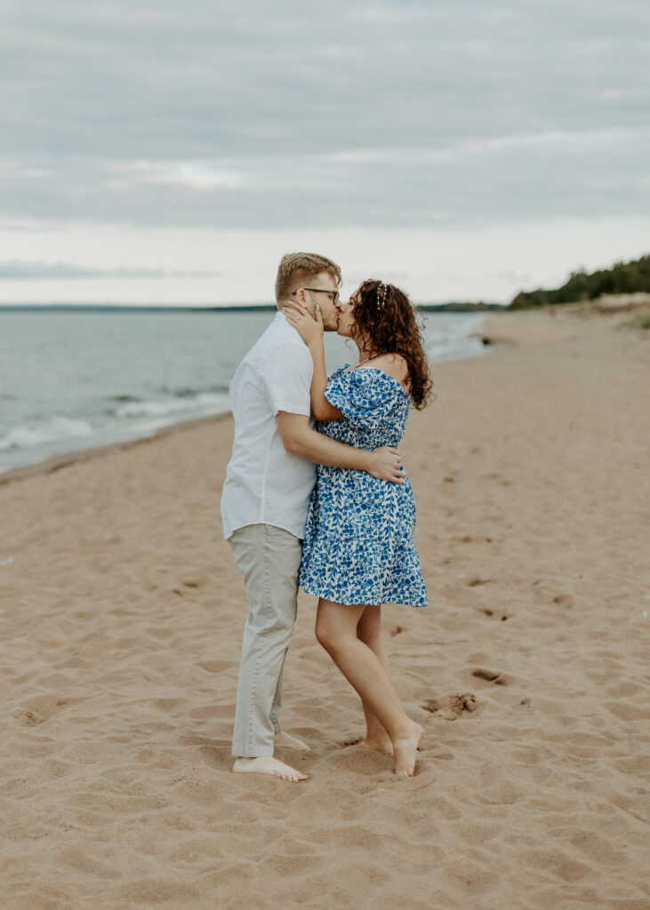 Couple kisses on the beach at Park Point Beach during their Duluth Minnesota engagement photo session