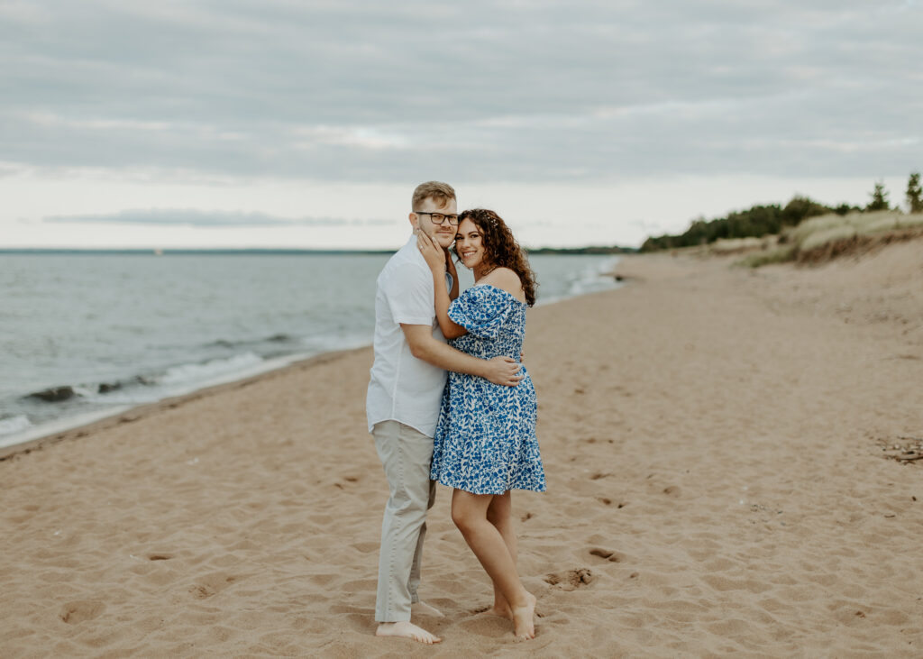 Couple embraces on the beach at Park Point Beach during their Duluth Minnesota engagement photo session