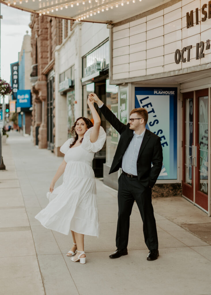 Couple twirls outside of Greysolon Ballroom during their Duluth Minnesota engagement photo session