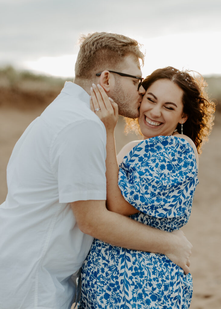 Couple embraces on the beach at Park Point Beach during their Duluth Minnesota engagement photo session