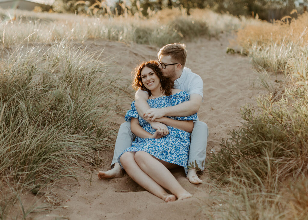 Couple embraces on the beach at Park Point Beach during their Duluth Minnesota engagement photo session