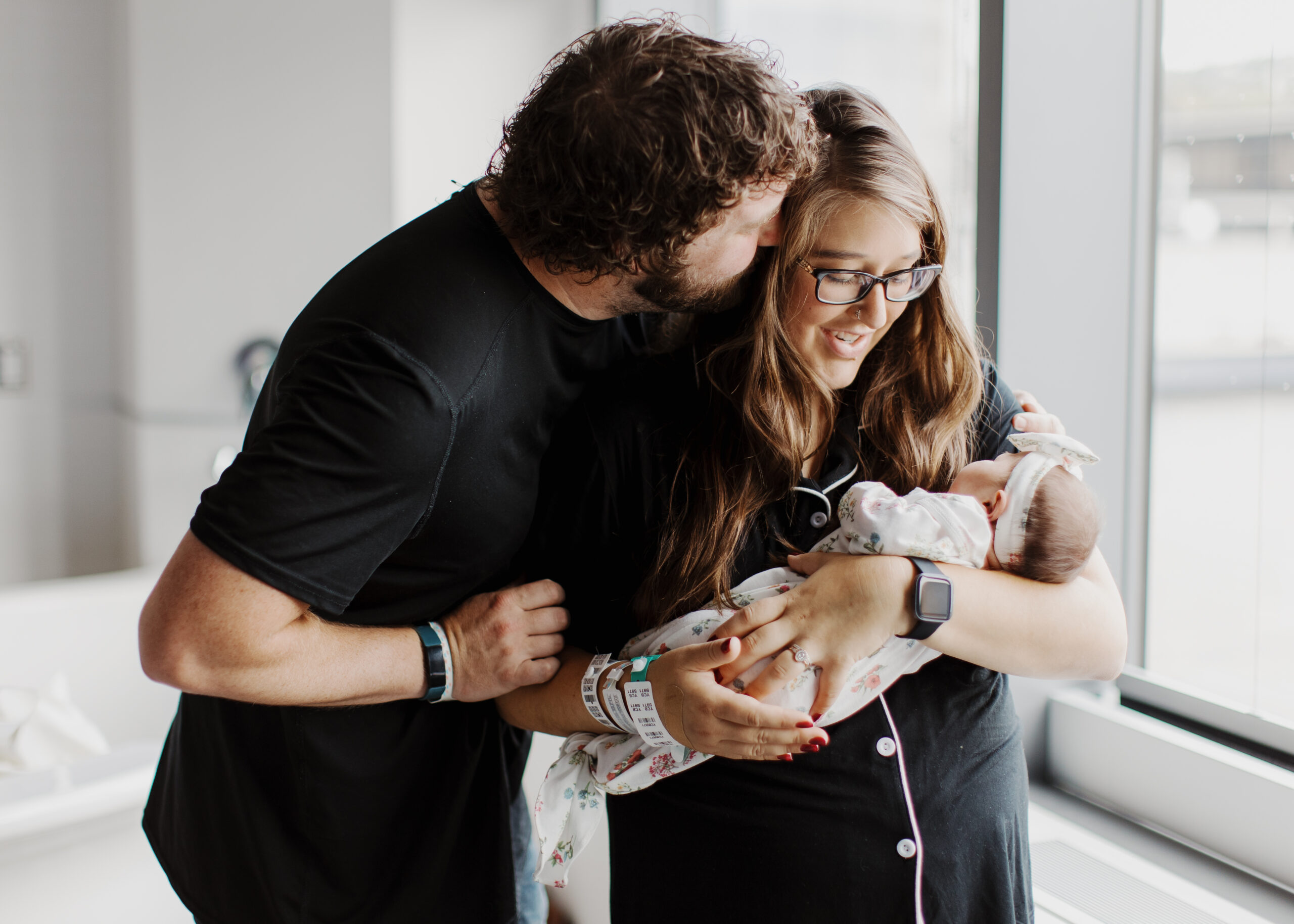 Mom and Dad embrace while holding newborn baby at Essentia Health Hospital in Duluth, Minnesota during Fresh 48 photo session