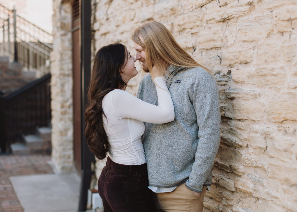 couple embraces during engagement photo session at St. Anthony Main in Minneapolis, Minnesota