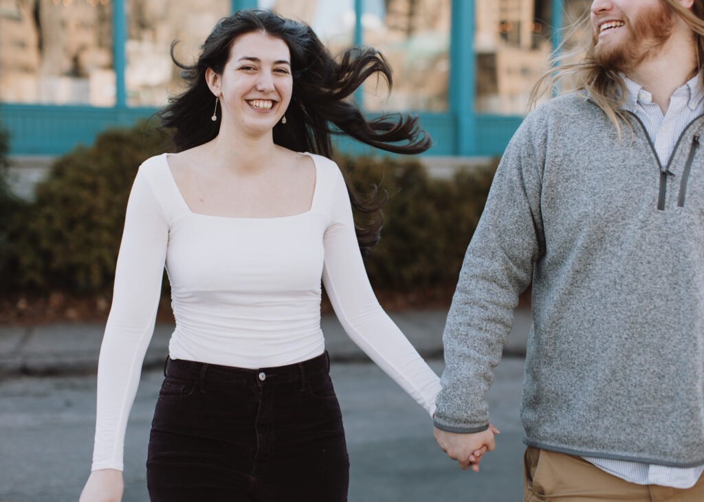 couple runs during engagement photo session at St. Anthony Main in Minneapolis, Minnesota